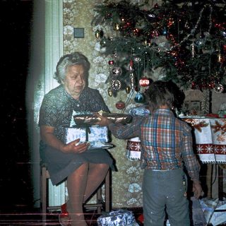 Woman wrapping holiday gifts with child nearby.