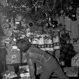 Family decorating Christmas tree with wrapped gifts.