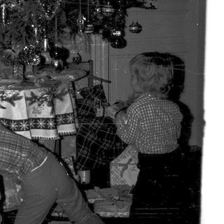 Family decorating Christmas tree with wrapped gifts.