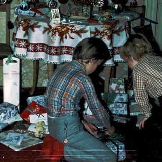 Two children decorating Christmas gifts under a decorated tree.