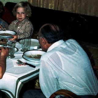 Family gathering eating dinner indoors together.
