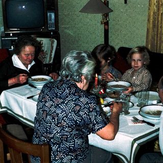 Family gathering eating dinner indoors together.