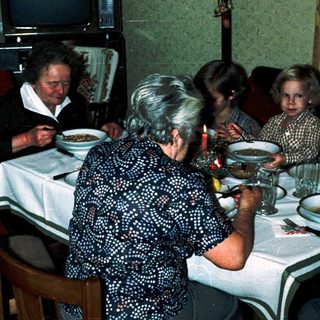 Family gathering eating dinner indoors together.
