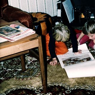 Two children examining a large map together indoors.