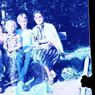Family posing together outdoors on park bench.