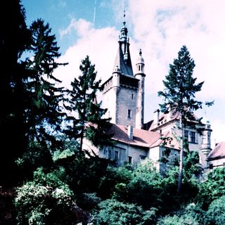 Majestic castle surrounded by lush greenery with people sitting nearby.