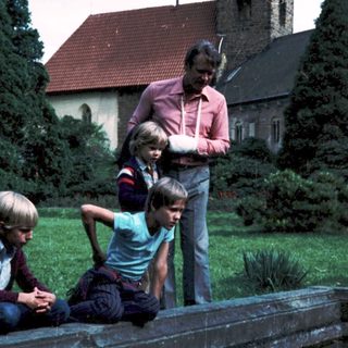 Family posing near church with pond.