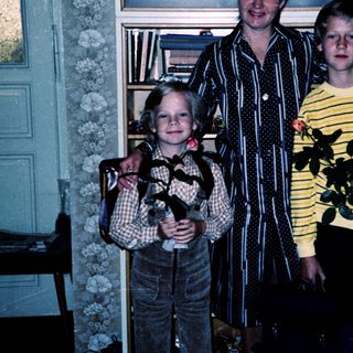 Family portrait with three people indoors holding plants.