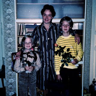 Family portrait with three people indoors holding plants.