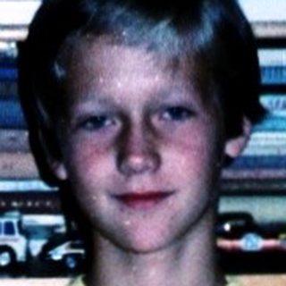 Boy posing with toy cars in a display case.