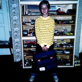 Boy posing with toy cars in a display case.