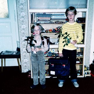 Two children holding stuffed animals indoors.