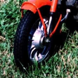 Young boy with adult on moped in rural field.
