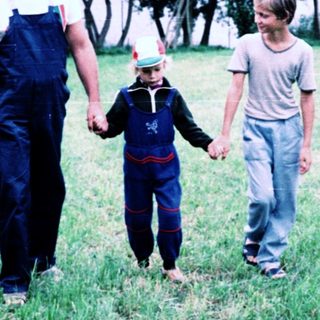 Family walking hand-in-hand in rural countryside.
