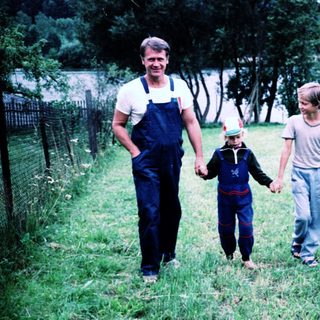 Family walking hand-in-hand in rural countryside.