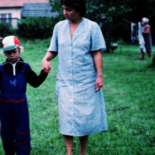 Family walking hand-in-hand in rural grassy field.