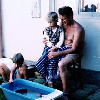 Family playing with water outdoors on lawn.