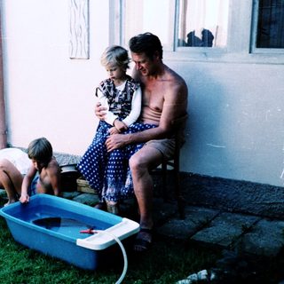Family playing with water outdoors on lawn.