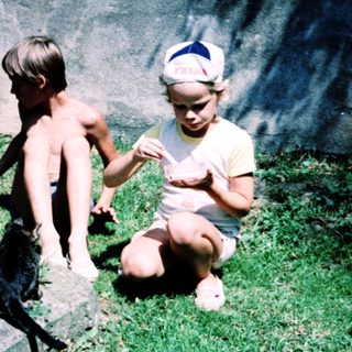 Two children interacting with cats outdoors.