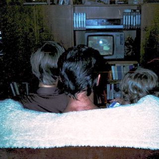 Three people watching old CRT TV together.
