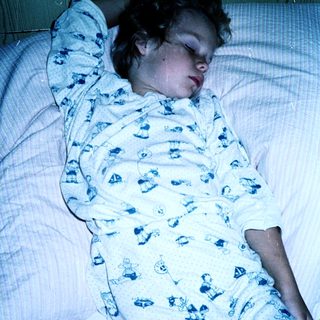 Child sleeping peacefully in pajamas on bed.