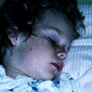 Child sleeping peacefully in pajamas on bed.
