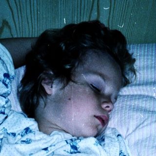 Child sleeping peacefully in pajamas on bed.