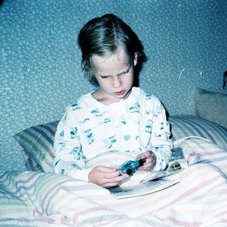A man and young girl playing video game together in bed.