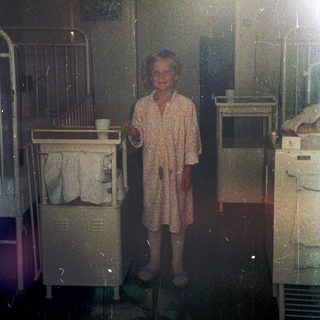 Child in pajamas holding cup in dimly lit room.