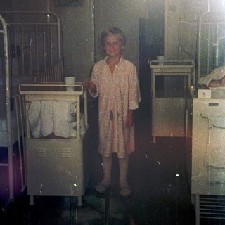 Child in pajamas holding cup in dimly lit room.