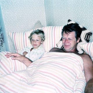A man and young child resting together in bed.
