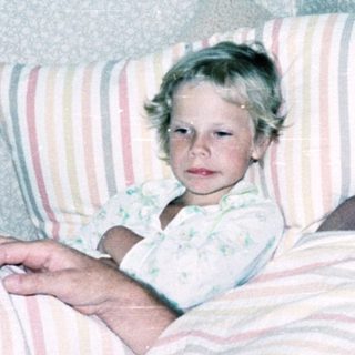A man and young child resting together in bed.