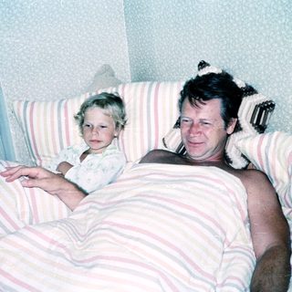 A man and young child resting together in bed.