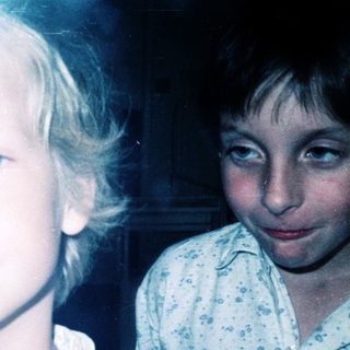 Two children posing indoors, mid-20th century style.