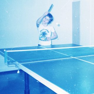 Two people playing indoor table tennis.