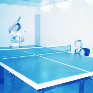 Two people playing indoor table tennis.