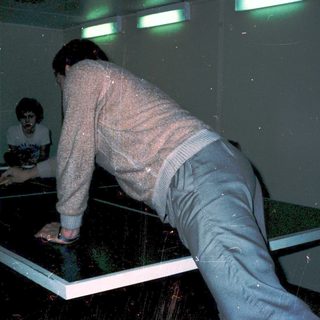 Two people playing table tennis in mirrored room.
