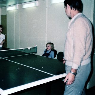 Family playing indoor table tennis together.