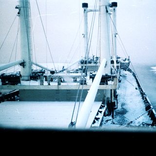Vintage ship navigating icy coastal waters.