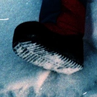 Child lying on snow with arms outstretched.