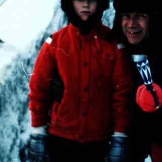 Three people dressed warmly walking on snowy stairs.