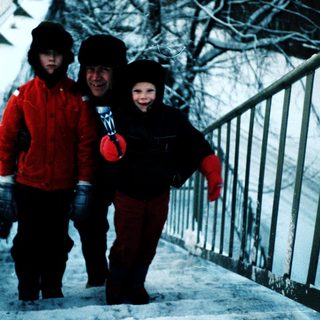 Three people dressed warmly walking on snowy stairs.