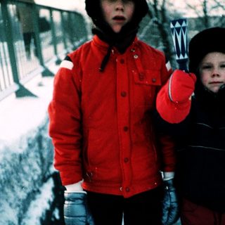 Two children playing in snow with snow tools.
