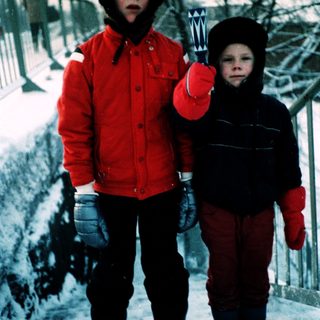 Two children playing in snow with snow tools.