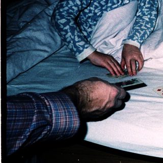 Two children playing board game with adult on bed.
