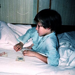 Two children playing board game with adult on bed.