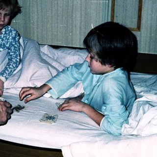 Family playing board game in hospital beds.