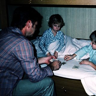 Family playing board game in hospital beds.