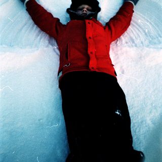 Person lying on snow with arms raised.