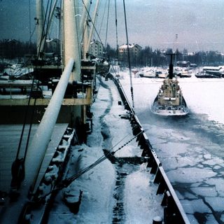 Ice-covered harbor with ship breaking through frozen water.